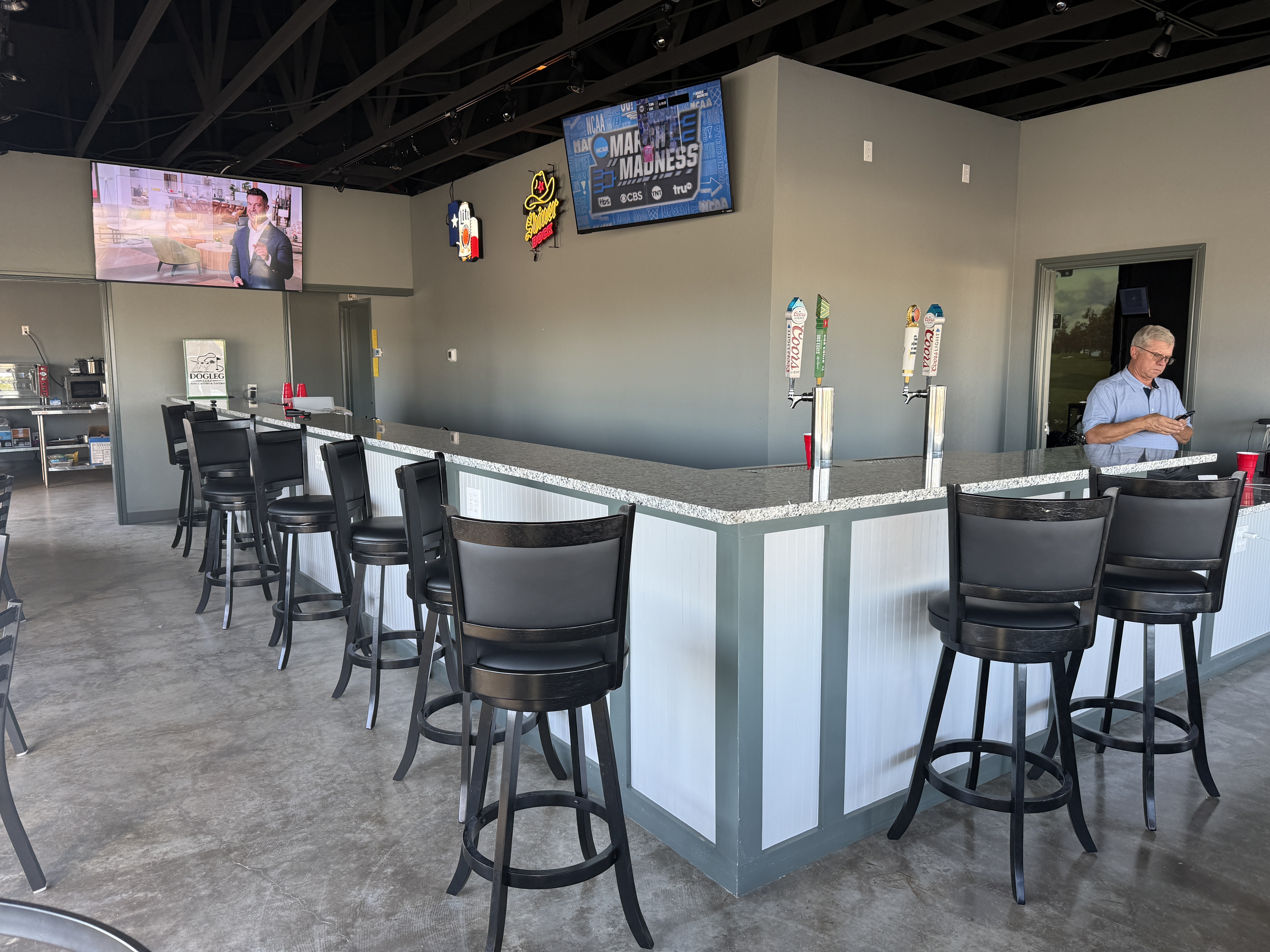 Dogleg Golf full bar area with granite countertop, barstools, beer taps, and TVs